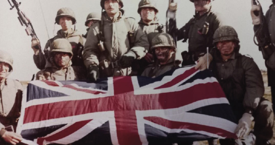 Fotografía de soldados argentinos posando con bandera del Reino Unido en como simbolo de victoria ante los ingleses.
